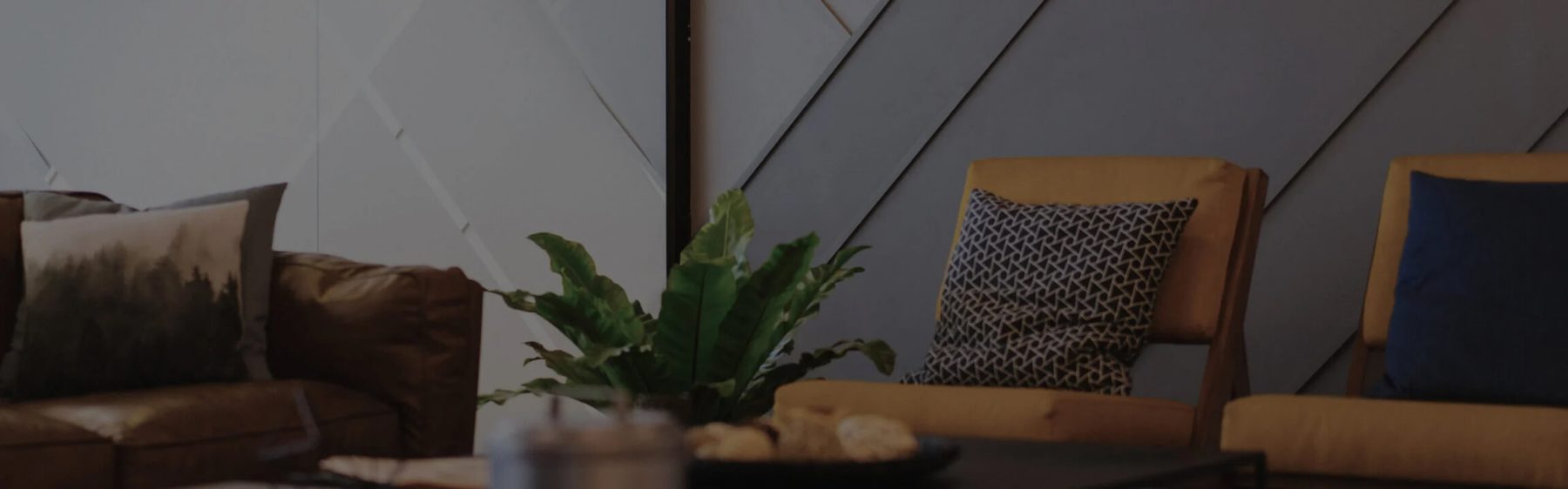 A warm, softly lit living space with a plant and patterned cushion